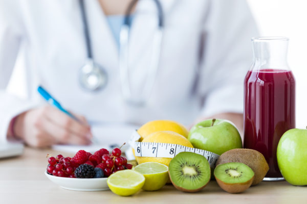 Close-up of some fruits such as apples, kiwis, lemons and berries on nutritionist table.